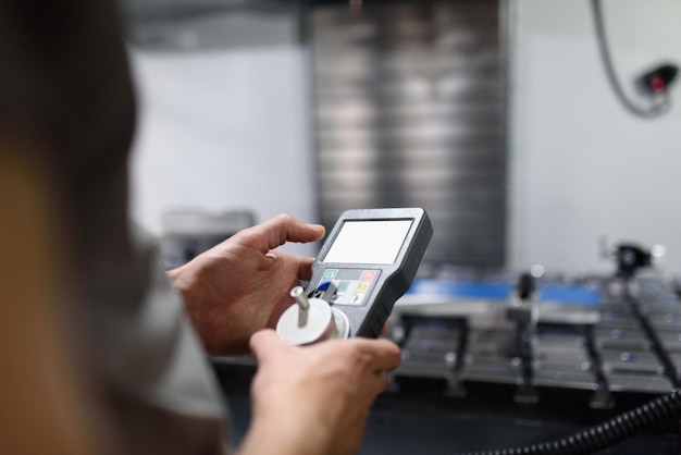 Trabajador ingresando datos en una máquina CNC en la planta de la fábrica para poner en marcha la producción