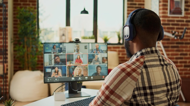 Trabajador de inicio que asiste a una reunión de videollamada en línea en casa, hablando con colegas en una llamada de teleconferencia. Usar cámara web en videoconferencia para chatear, trabajar desde casa de forma remota en el escritorio.