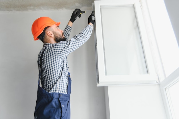 Trabajador en la instalación de una ventana de upvc de plástico blanco en la casa