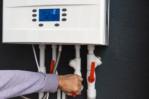 Trabajador instalando una caldera de gas de doble circuito para la calefacción doméstica de invierno y la calefacción de agua