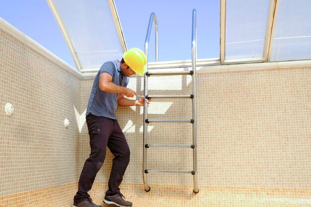 Foto trabajador instalando una escalera de piscina en una piscina vacía