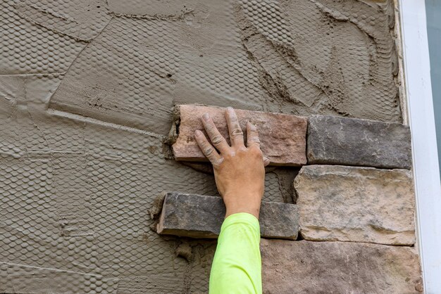 Foto un trabajador está instalando ladrillo de piedra decorativo en la pared