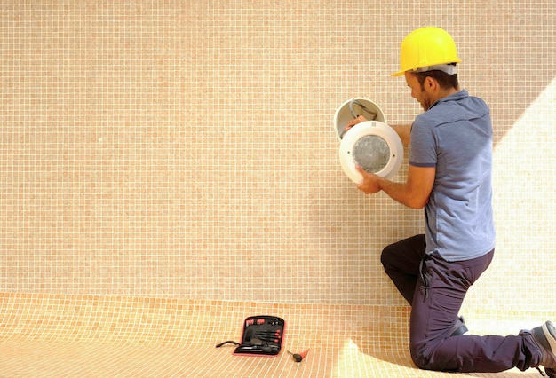 trabajador instalando luces en una piscina vacante en construcción