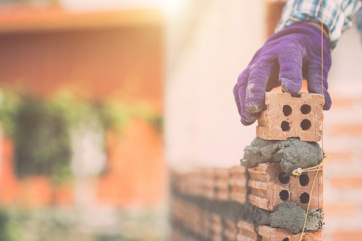 Trabajador instalando paredes de ladrillos en proceso de construcción de viviendas