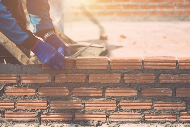 Trabajador instalando paredes de ladrillos en proceso de construcción de viviendas