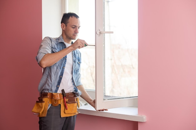 El trabajador instalando y revisando la ventana de la casa.