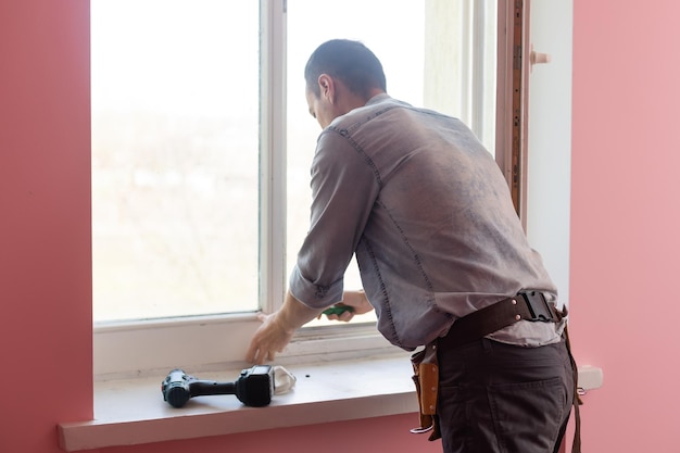 El trabajador instalando y revisando la ventana de la casa.