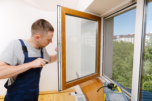 El trabajador instalando y revisando la ventana de la casa.