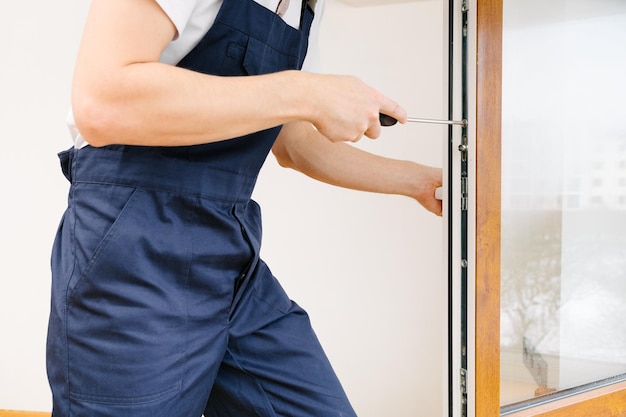 El trabajador instalando y revisando la ventana de la casa.