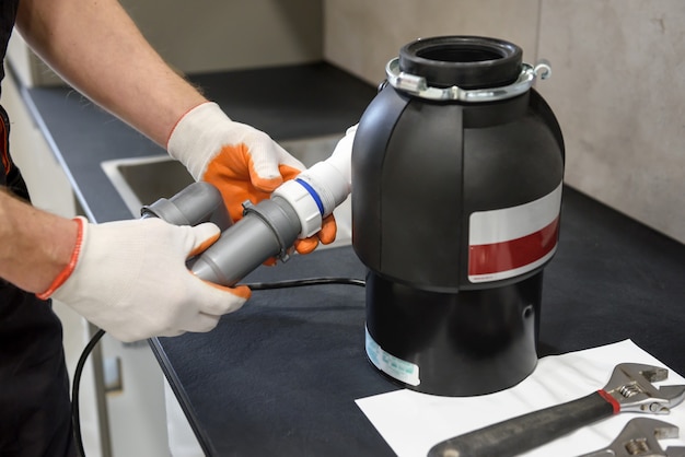 Trabajador instalando una trituradora de residuos domésticos para el fregadero de la cocina de cerca