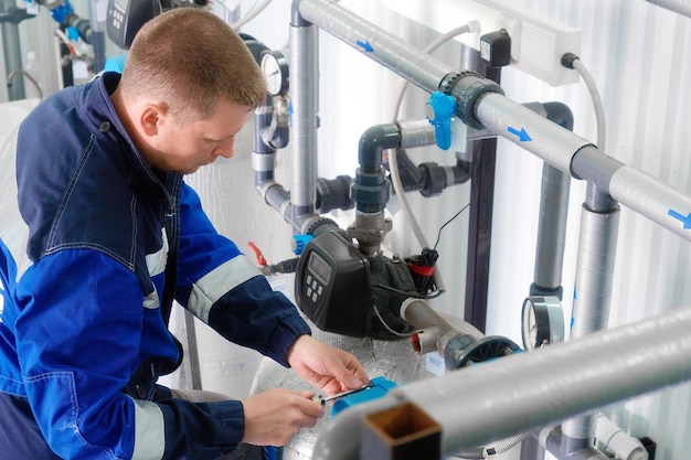 Trabajador interior con tuberías repara sistema de suministro de agua industrial Diagnóstico de suministro de agua