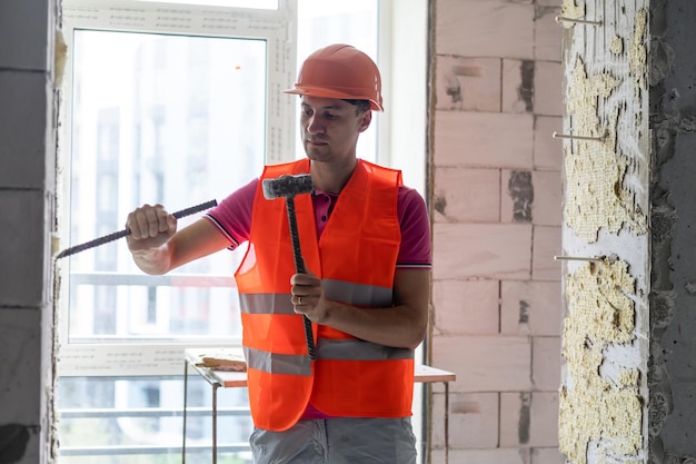 Trabajador joven que sostiene un martillo y un cincel puntiagudo