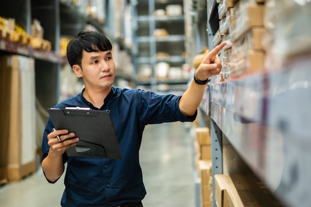 Trabajador joven sosteniendo el portapapeles y comprobando el inventario en la tienda del almacén