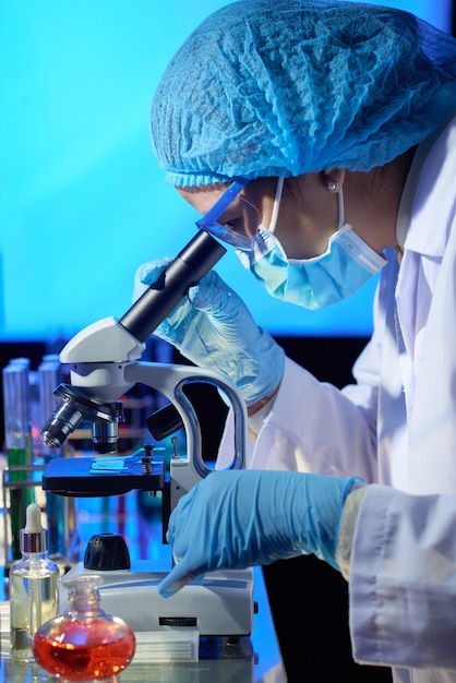 Trabajador de laboratorio mirando a través del microscopio