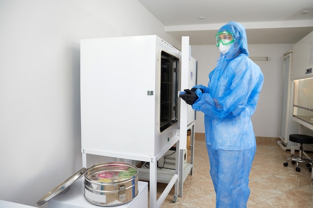 Trabajador de laboratorio que opera esterilizador de autoclave de laboratorio moderno