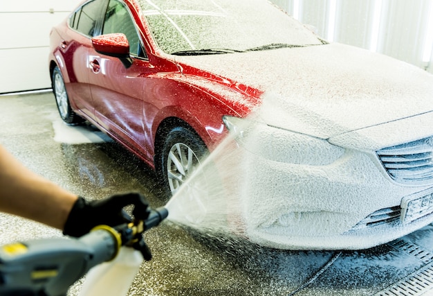 Limpieza del coche con espuma activa. Hombre lavando su coche en