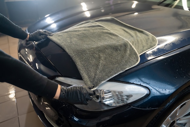 Trabajador de lavado de coches limpia el coche después del lavado