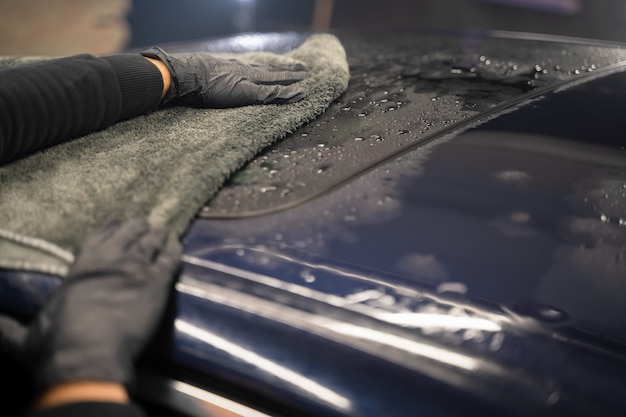 Trabajador de lavado de coches limpia el coche después del lavado