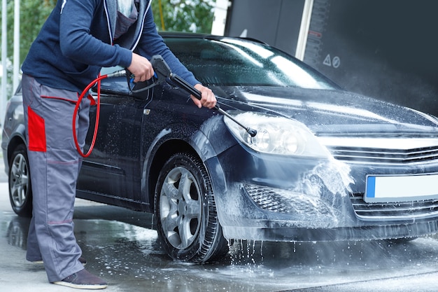 Trabajador de lavado de coches profesional está lavando el coche del cliente