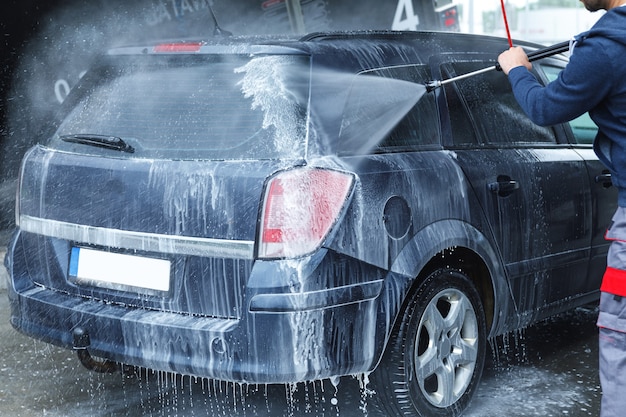 Trabajador de lavado de coches profesional está lavando el coche del cliente