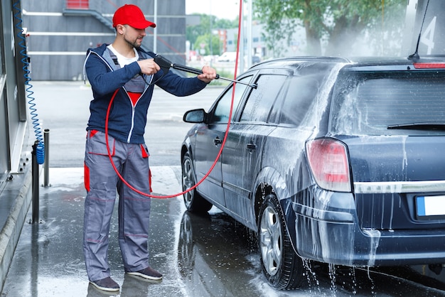 Foto trabajador de lavado de coches profesional está lavando el coche del cliente
