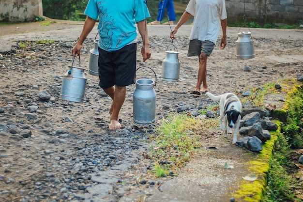 El trabajador lechero tradicional o el lechero en Boyolali Indonesia traen un recipiente de leche brillante de metal o una lata tradicional de una granja tradicional