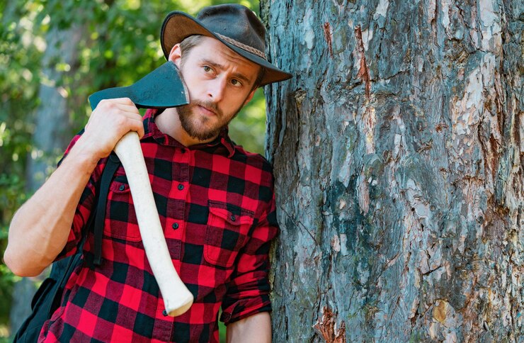 Foto trabajador leñador de pie en el bosque con hacha leñador sosteniendo el hacha hombre fuerte leñador