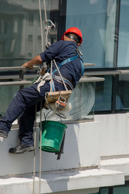 trabajador limpiando el vidrio a la altura de un edificio