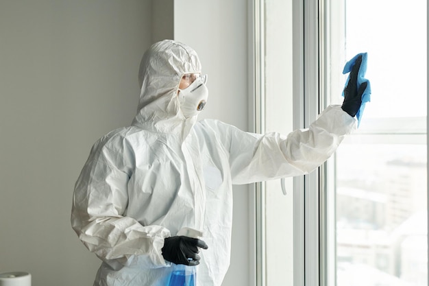 Trabajador de limpieza en traje limpiando ventanas