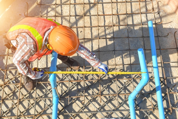 Trabajador con líneas de hierro de construcción para la construcción de cimientos, Trabajador de la construcción