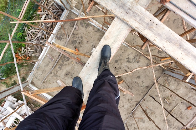 El trabajador lleva puesto de arranque en andamios de madera en el sitio de construcción.