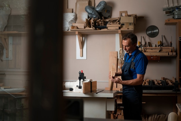 Foto trabajador de la madera en su taller trabajando con herramientas y equipos.