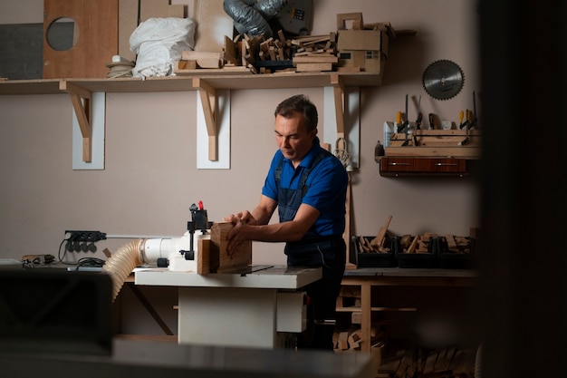 Foto trabajador de la madera en su taller trabajando con herramientas y equipos.