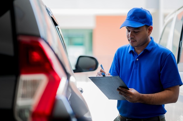 Un trabajador de mantenimiento de automóviles está revisando una lista de elementos para el mantenimiento de automóviles de un cliente del taller.