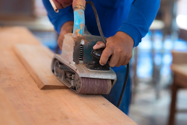 Trabajador manual muele la madera con la máquina lijadora