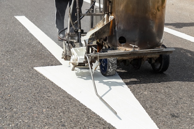 Trabajador y máquina de pintura trabajan en la calle en Tailandia