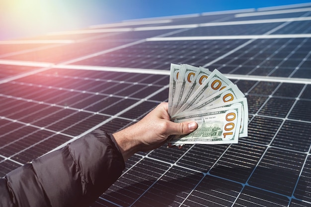 Un trabajador maravilloso tiene una cantidad redonda de dinero para la instalación de paneles solares en sus manos