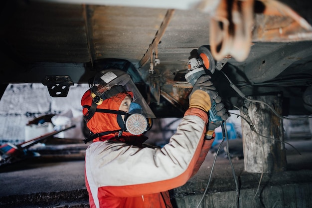 trabajador masculino aserrando metal con un molinillo en un automóvil