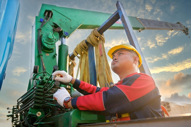 Trabajador masculino asiático Trabajador que opera a mano una grúa en un sitio de construcción para levantar equipos de construcción pesados en el sitio de construcción