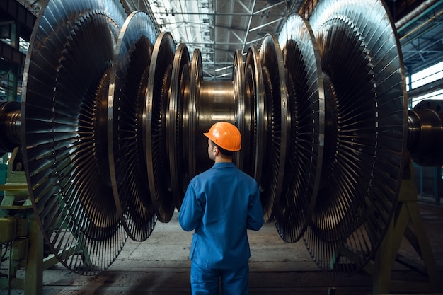 Trabajador masculino comprueba las paletas del impulsor de la turbina en la fábrica.