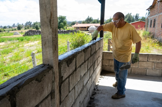 Un trabajador masculino construyendo una pared con bloques de brisa.