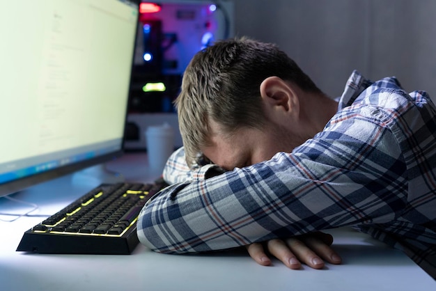 Un trabajador masculino enfermo y cansado en la noche haciendo algún trabajo en el concepto de exceso de trabajo de oficina