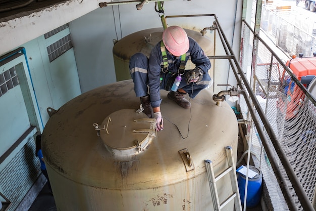 Foto el trabajador masculino es el techo de espesor ultrasónico del tanque de acero inoxidable para la inspección