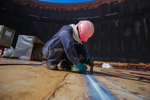 Trabajador masculino prueba tanque de acero soldadura a tope placa inferior de carbono del tanque de almacenamiento fondo de aceite contraste blanco de prueba de campo magnético