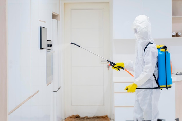 Trabajador masculino rociando desinfectante en la cocina de la casa