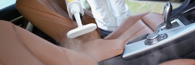 Trabajador de materiales peligrosos limpiando el interior del automóvil con desinfectante en aerosol y calor de vapor