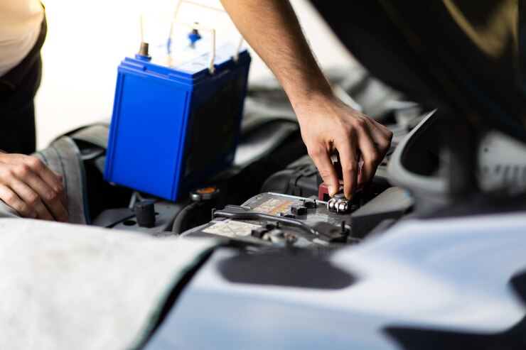 Trabajador mecánico de automóviles comprobando y cambiando la batería del coche. Concepto de garaje de mantenimiento y servicio automático de automóviles.