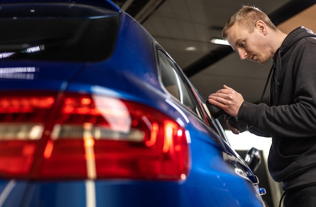 Trabajador mecánico de automóviles que pule el automóvil en una reparación de automóviles y renueve la tienda de la estación de servicio por power b