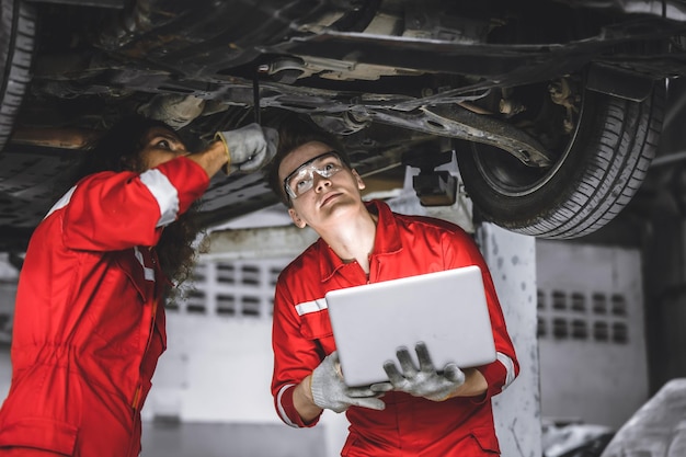 Trabajador mecánico del equipo masculino trabajando juntos bajo el ajuste de verificación del servicio automático del automóvil en el garaje