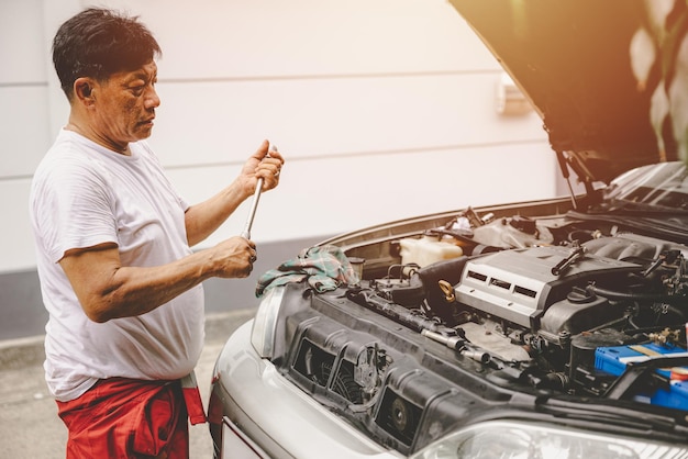 Trabajador mecánico de garaje masculino asiático arreglar reemplazar el servicio del motor de aceite reparar el automóvil roto